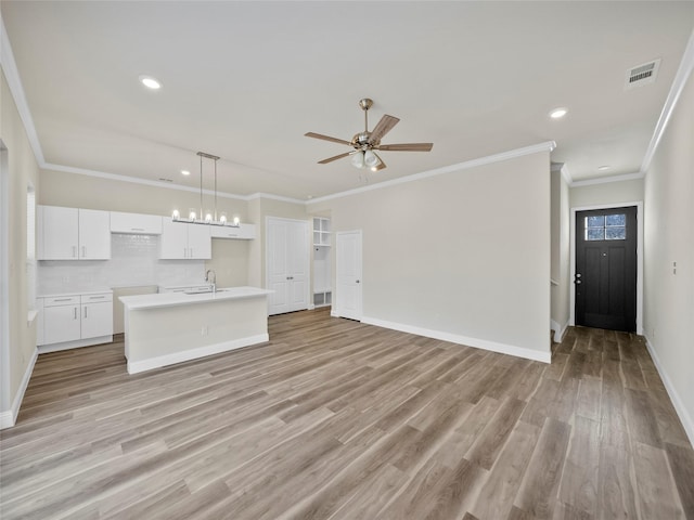 unfurnished living room with light wood finished floors, a sink, visible vents, and baseboards