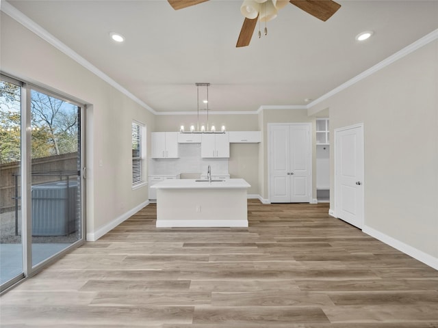 kitchen with light wood finished floors, a center island with sink, baseboards, white cabinetry, and a sink