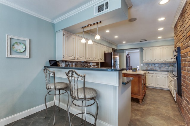 kitchen featuring ornamental molding, stainless steel fridge, visible vents, and a peninsula