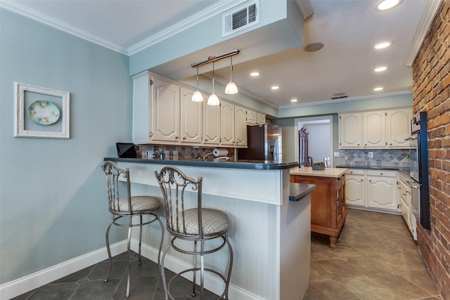 kitchen with a peninsula, appliances with stainless steel finishes, crown molding, tasteful backsplash, and a breakfast bar area
