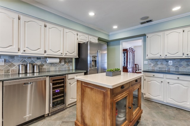 kitchen with wine cooler, appliances with stainless steel finishes, white cabinetry, ornamental molding, and tasteful backsplash