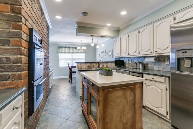 kitchen featuring appliances with stainless steel finishes, crown molding, white cabinetry, decorative backsplash, and a kitchen island