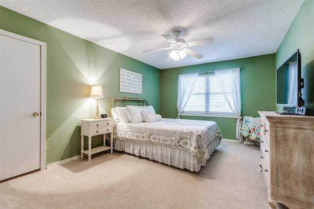 bedroom featuring baseboards, a textured ceiling, a ceiling fan, and light colored carpet