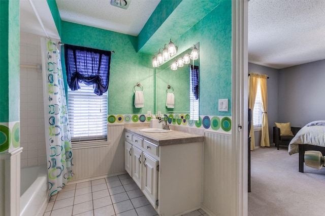 ensuite bathroom with a textured ceiling, shower / tub combo, a wainscoted wall, vanity, and tile patterned flooring