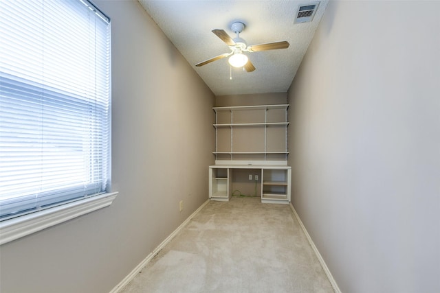 unfurnished office featuring light carpet, a ceiling fan, baseboards, and a textured ceiling