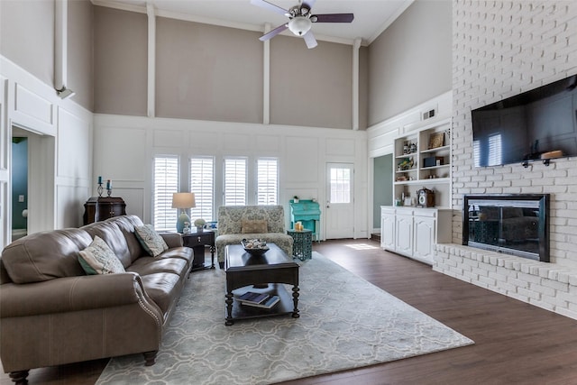 living area featuring crown molding, a brick fireplace, a decorative wall, and built in features