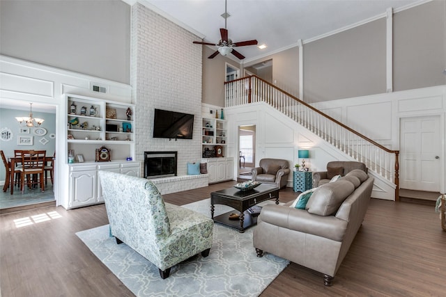 living area with visible vents, a decorative wall, stairway, dark wood-type flooring, and a brick fireplace