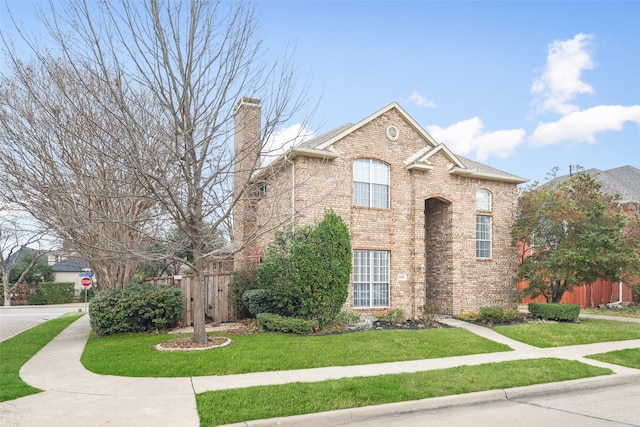 view of front of house featuring a chimney, fence, a front lawn, and brick siding