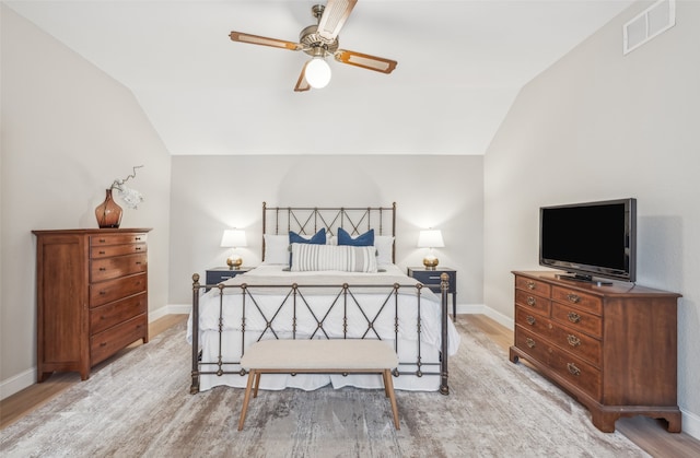 bedroom with light wood-style floors, lofted ceiling, visible vents, and baseboards