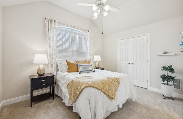 bedroom featuring lofted ceiling, a closet, light colored carpet, and baseboards