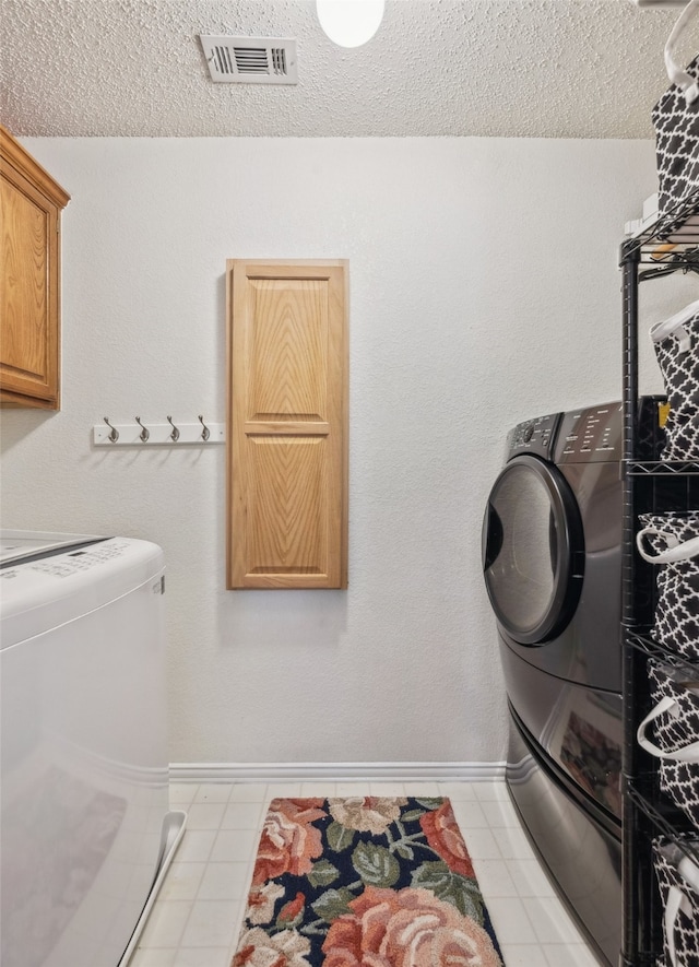 laundry room featuring cabinet space, visible vents, separate washer and dryer, and a textured ceiling