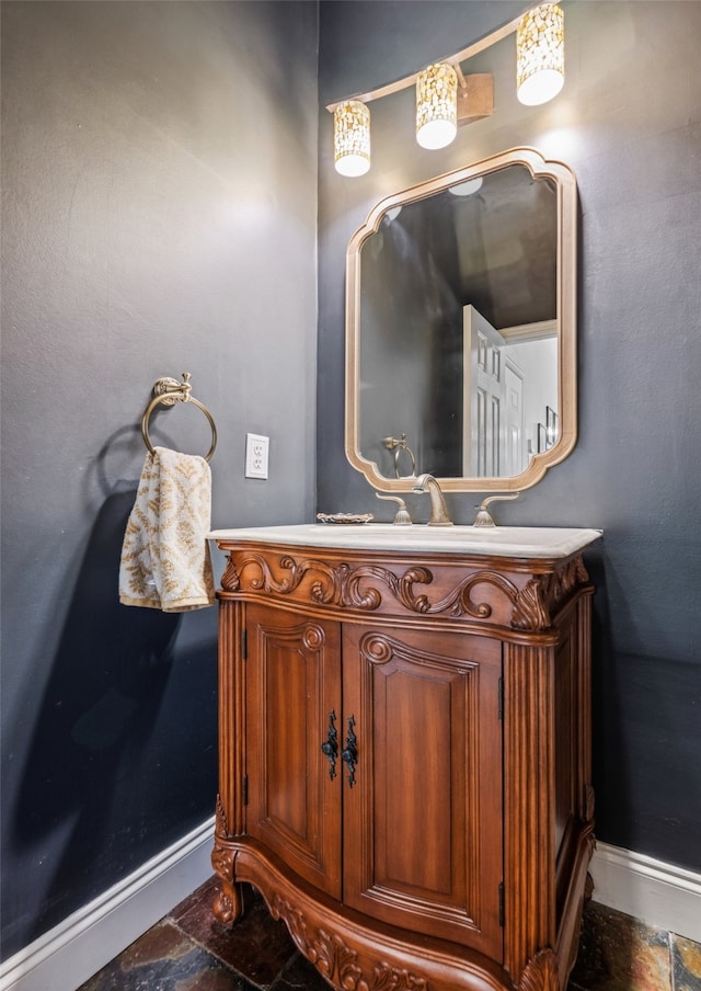 bathroom featuring baseboards, stone tile flooring, and vanity