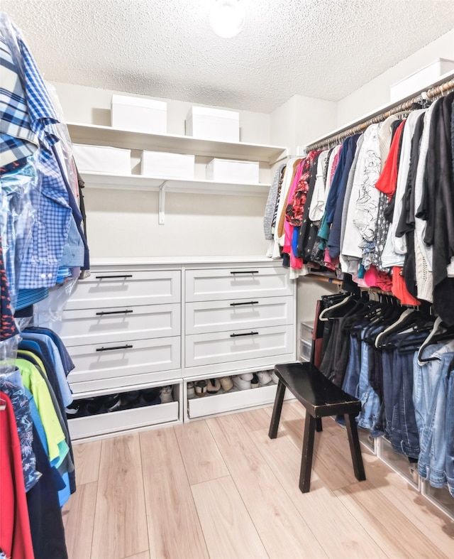 walk in closet with light wood-style floors