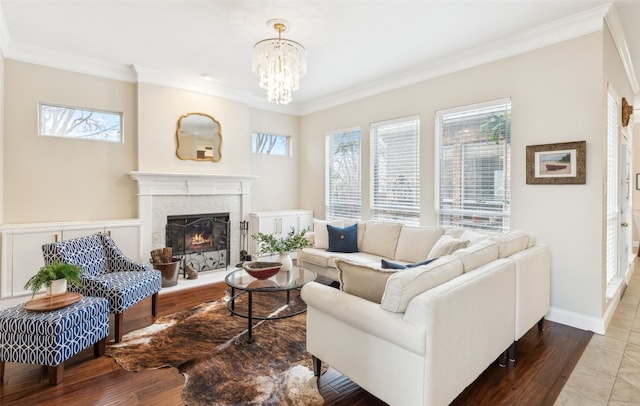 living area with baseboards, a lit fireplace, ornamental molding, and wood finished floors