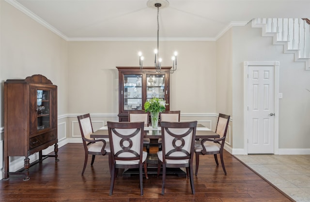 dining area with ornamental molding, a decorative wall, wood finished floors, and an inviting chandelier