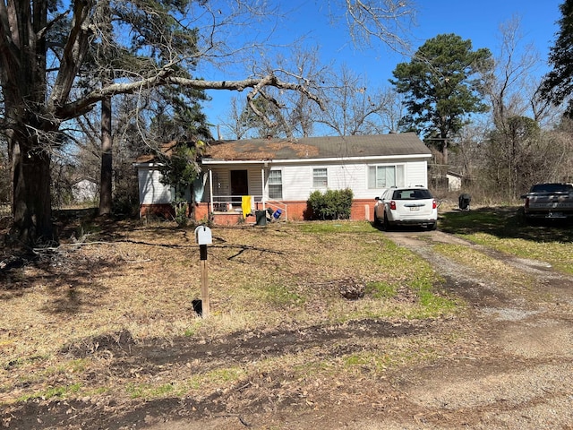 view of front of house with dirt driveway, a porch, and brick siding