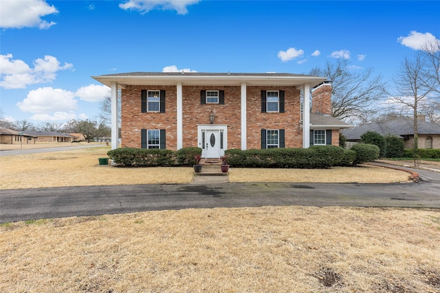 neoclassical / greek revival house with brick siding and a chimney