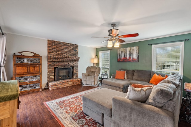 living area featuring a brick fireplace, wood finished floors, a ceiling fan, and crown molding