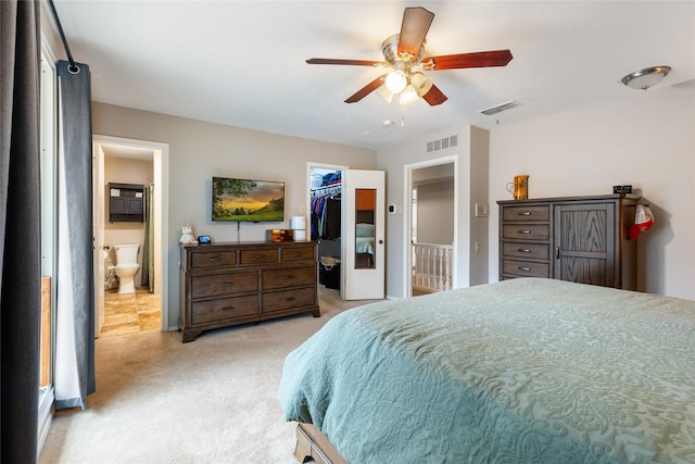 bedroom with a closet, light colored carpet, a walk in closet, and visible vents