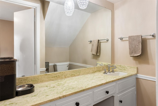 bathroom featuring lofted ceiling, vanity, and toilet