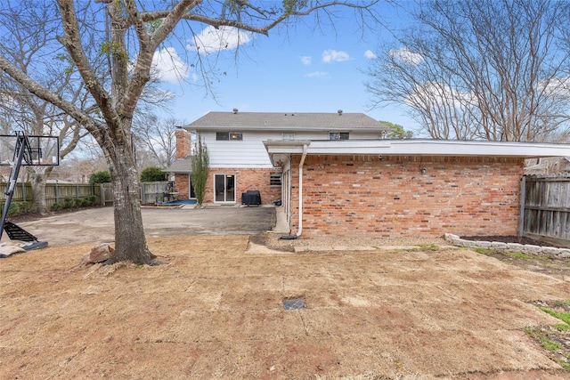 back of property with central AC unit, a patio, a chimney, fence, and brick siding