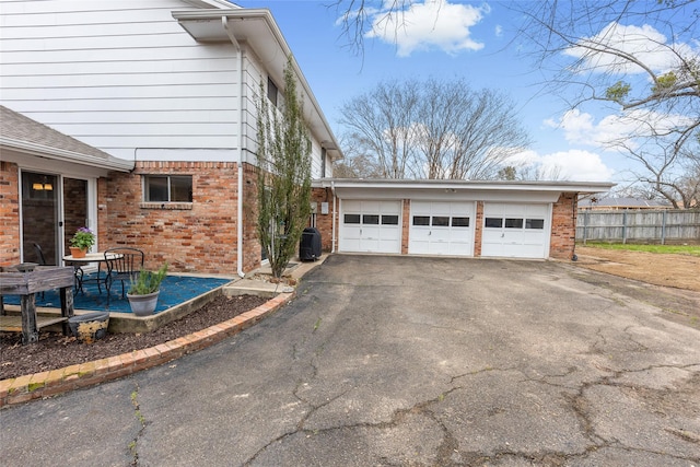 view of side of property featuring a garage, fence, central AC, and brick siding