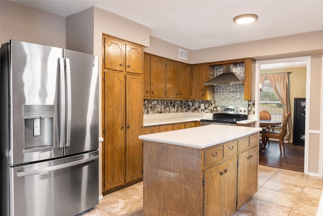 kitchen featuring visible vents, light countertops, appliances with stainless steel finishes, wall chimney range hood, and tasteful backsplash