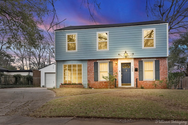 colonial house with brick siding, a detached garage, fence, driveway, and a front lawn