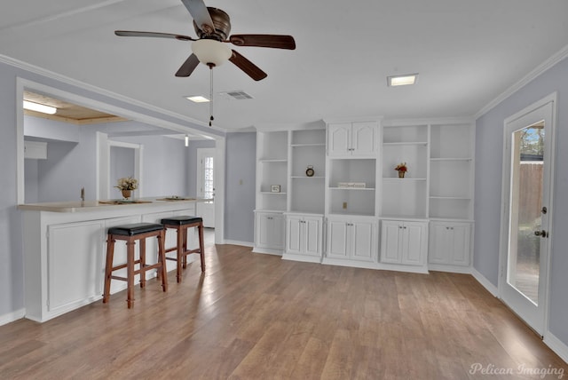 interior space featuring light wood-style floors, baseboards, visible vents, and ornamental molding