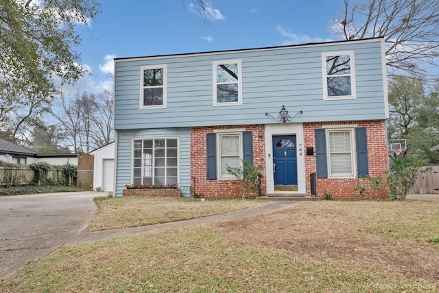 colonial-style house featuring a garage, brick siding, fence, driveway, and a front lawn