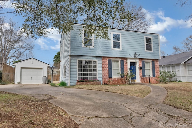 colonial home with a garage, concrete driveway, an outbuilding, fence, and brick siding