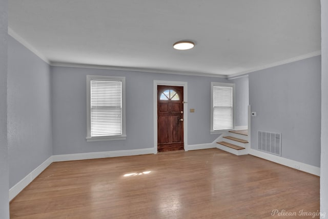 entryway featuring ornamental molding, visible vents, baseboards, and wood finished floors