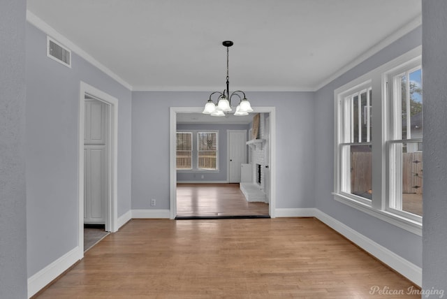 unfurnished dining area featuring baseboards, visible vents, a notable chandelier, and wood finished floors