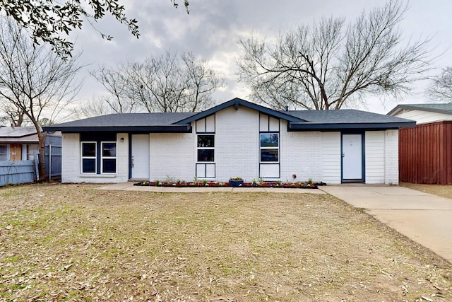 view of front of home featuring brick siding, fence, and a front lawn