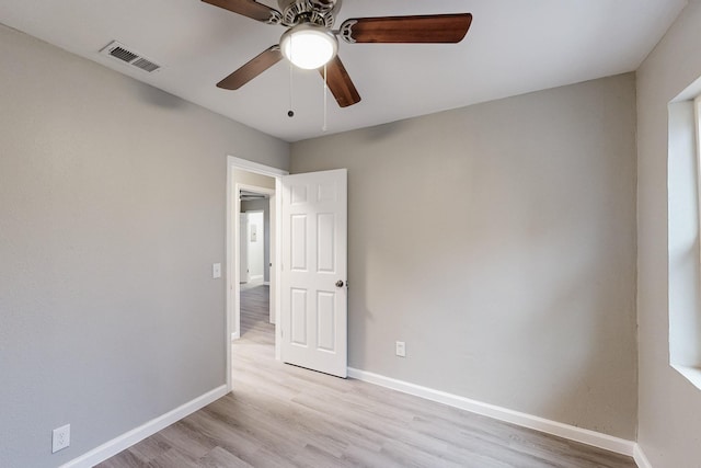 spare room featuring ceiling fan, light wood-type flooring, visible vents, and baseboards