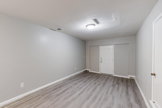 spare room featuring attic access, visible vents, baseboards, and wood finished floors