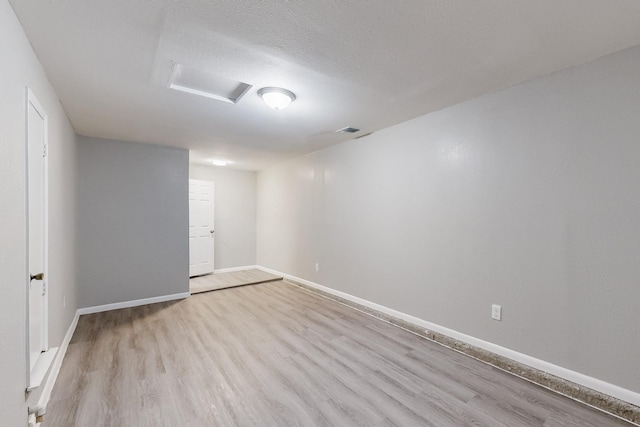 empty room featuring attic access, baseboards, visible vents, wood finished floors, and a textured ceiling