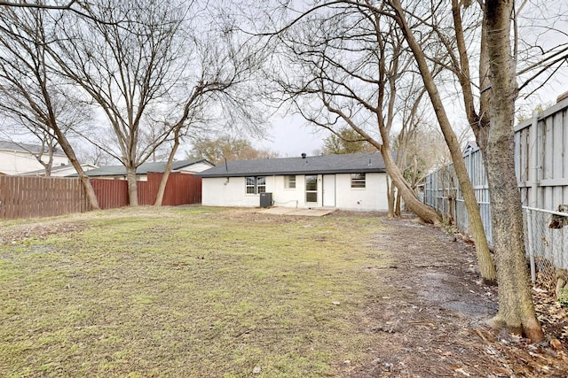 rear view of house with central air condition unit, a fenced backyard, and a lawn