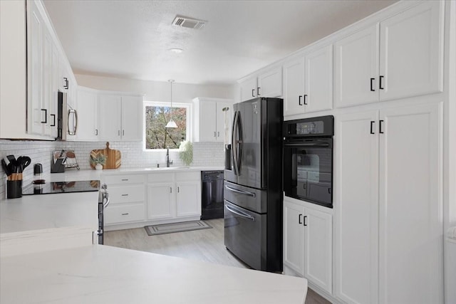 kitchen with tasteful backsplash, visible vents, white cabinets, a sink, and black appliances