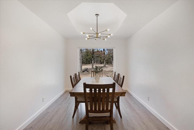 dining space featuring an inviting chandelier, wood finished floors, and baseboards