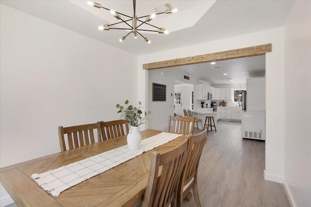 dining room with a notable chandelier, light wood-type flooring, visible vents, and baseboards