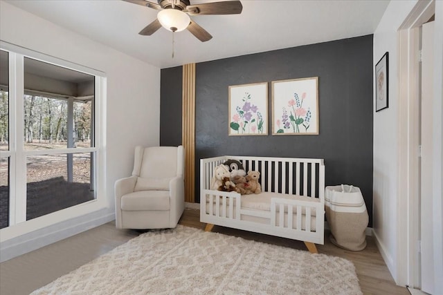 bedroom with a ceiling fan, baseboards, and wood finished floors