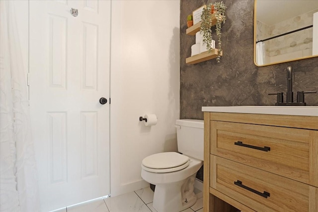 bathroom featuring marble finish floor, baseboards, vanity, and toilet