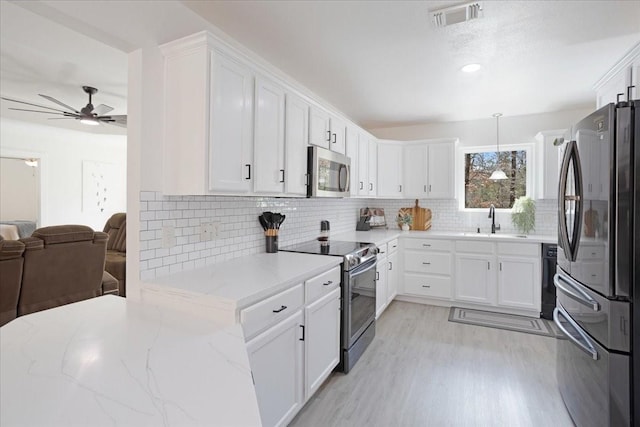 kitchen featuring visible vents, white cabinets, appliances with stainless steel finishes, open floor plan, and a sink