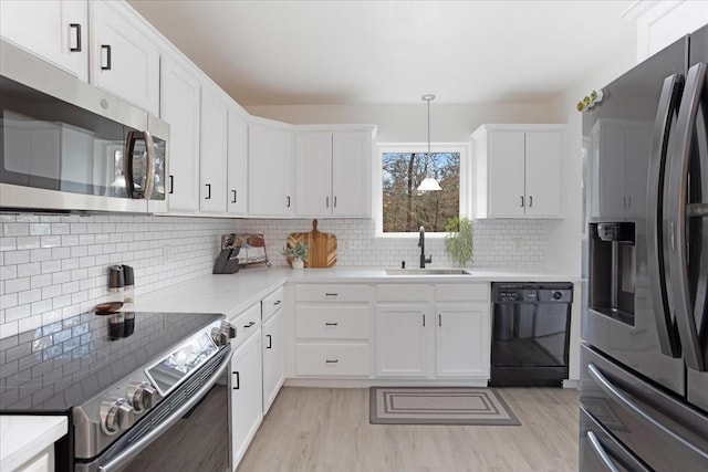 kitchen with white cabinets, decorative backsplash, appliances with stainless steel finishes, light countertops, and a sink