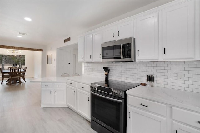 kitchen featuring appliances with stainless steel finishes, visible vents, a peninsula, and white cabinetry