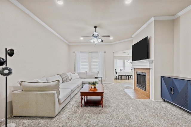 living area with ceiling fan, recessed lighting, a tiled fireplace, carpet, and crown molding