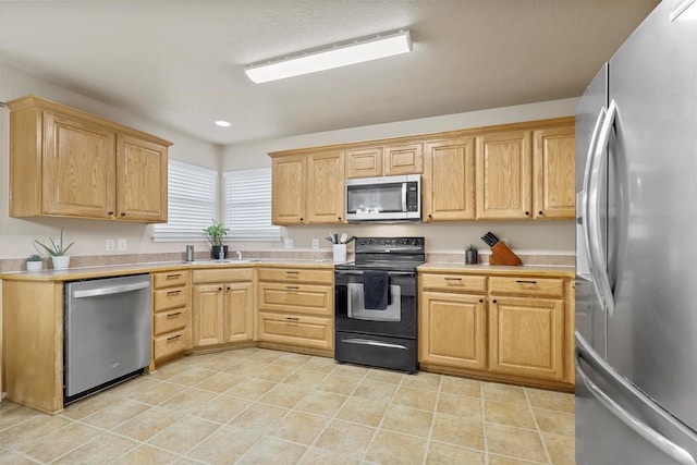 kitchen featuring light tile patterned flooring, stainless steel appliances, light countertops, and light brown cabinetry