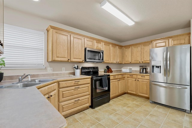 kitchen with light brown cabinets, stainless steel appliances, a sink, and light countertops