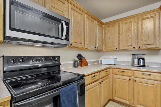 kitchen featuring black range with electric cooktop, light countertops, and stainless steel microwave